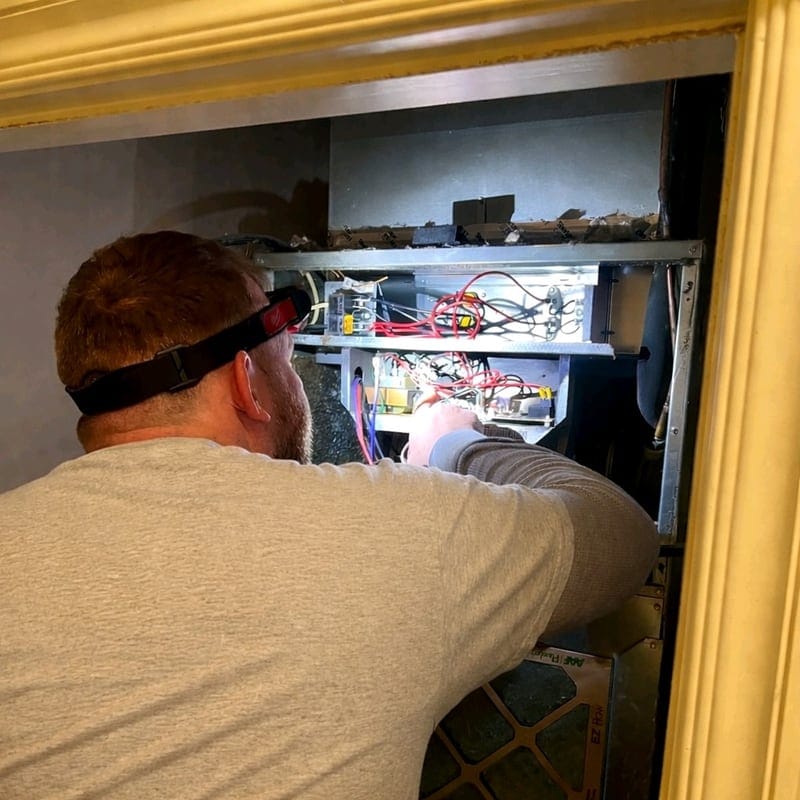 HVAC technician working inside a furnace