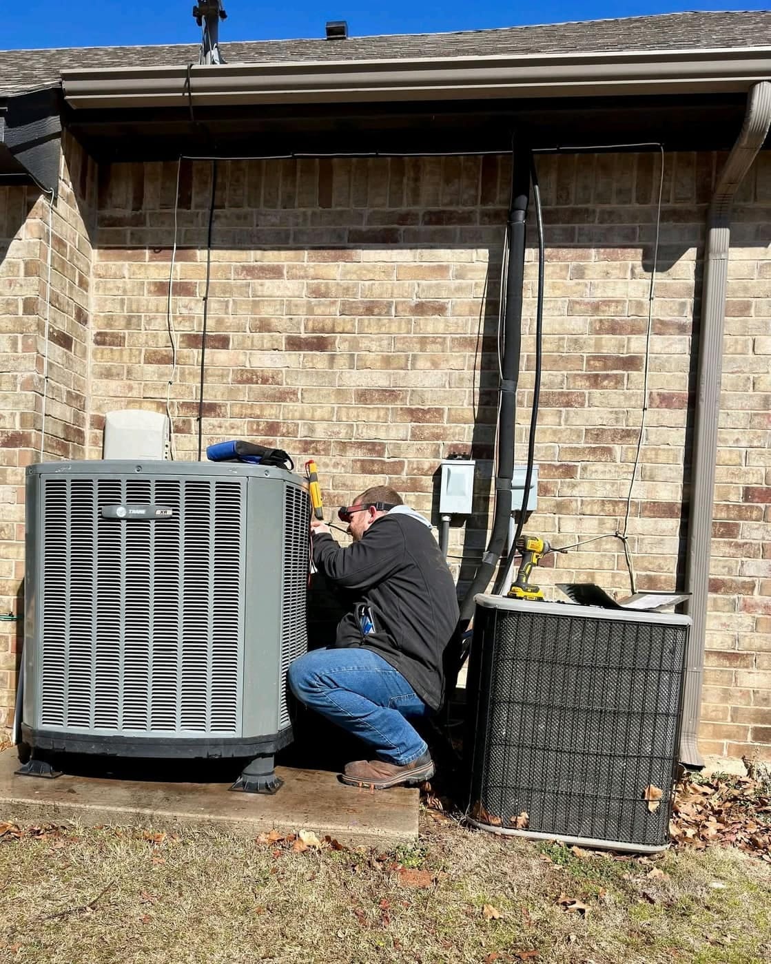 HVAC technician servicing an outdoor condenser in Oklahoma City
